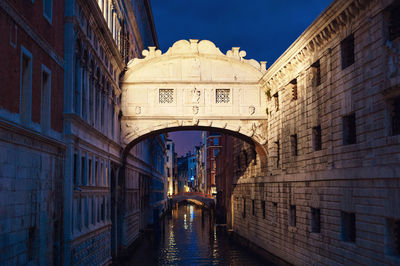 Arch bridge over canal amidst buildings in city