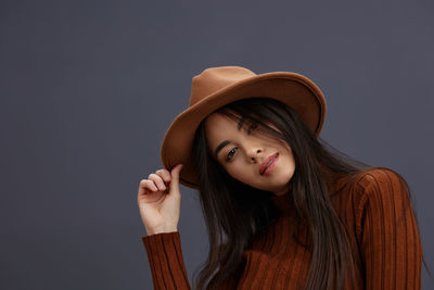 Young woman wearing hat against colored background