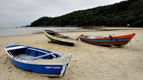 Boat moored on beach against sky