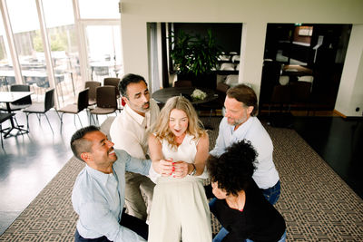 Playful businessmen and businesswoman lifting female colleague at convention center