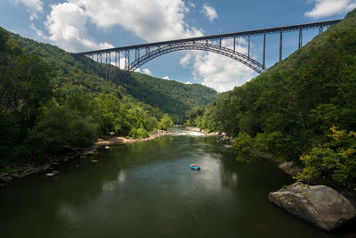 Bridge over river in forest against sky