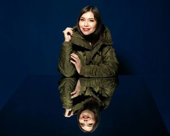 Portrait of smiling young woman against black background