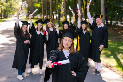 Portrait of smiling friends wearing graduation gown