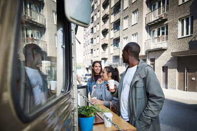 Male and female friends talking at food truck in city