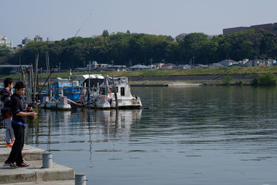 Man standing on riverbank against clear sky