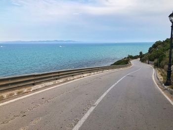 Scenic view of road by sea against sky