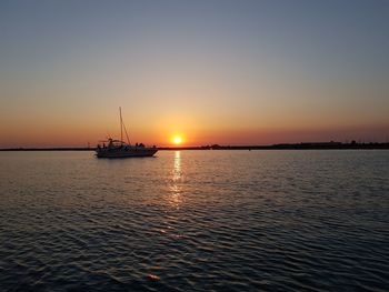 Sailboat sailing on sea against clear sky during sunset