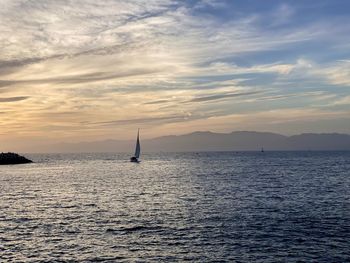 Sailboat sailing on sea against sky during sunset