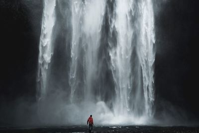 Rear view of man against waterfall
