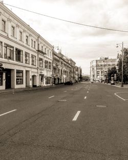 Road by buildings in city against sky