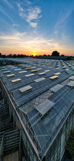 Aerial side view of large industrial greenhouses for growing plants in winter at sunset.