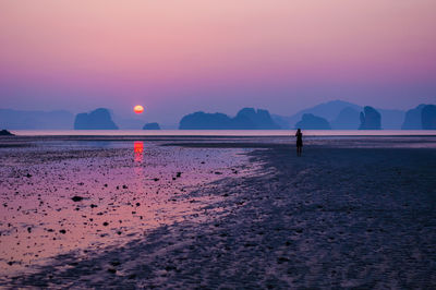 Silhouette person standing on beach against sky during sunset