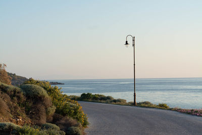 Road by sea against clear sky