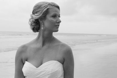 Close-up of woman looking away while standing at beach against sky