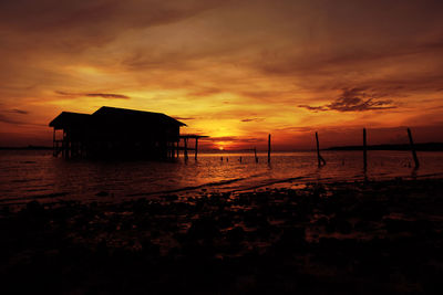 Silhouette people on beach against orange sky