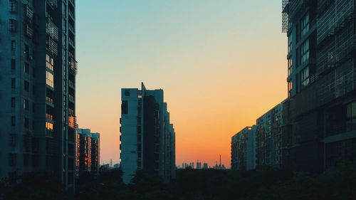 Modern cityscape against clear sky during sunset