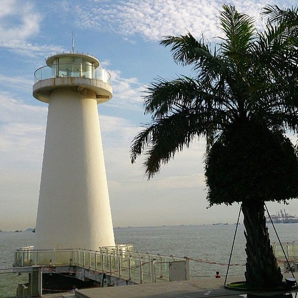 sea, water, horizon over water, sky, lighthouse, tranquility, scenics, tranquil scene, built structure, nature, beach, cloud - sky, beauty in nature, guidance, architecture, tree, cloud, protection, shore, idyllic