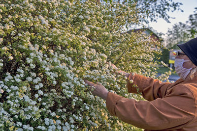 Side view of woman touching plants outdoors