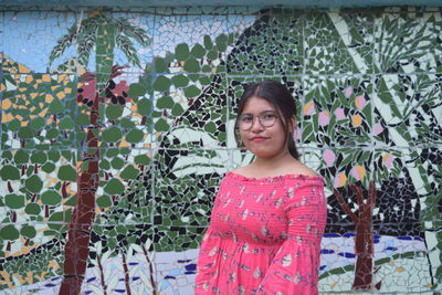 Portrait of woman standing against wall