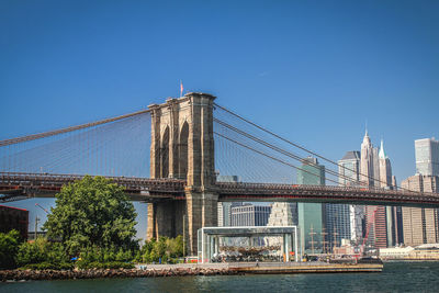 Brooklyn bridge over east river against clear blue sky