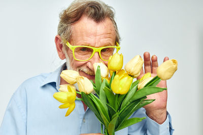 Portrait of senior man with tulip against white background