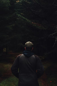 Rear photo of male walking through dark forest.