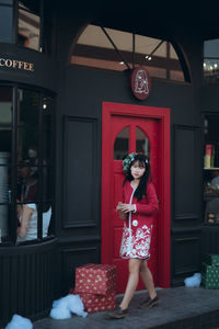 Portrait of young woman standing against window