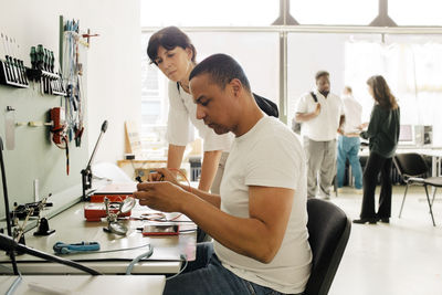 Repairman examining smart phone while sitting near female customer at store