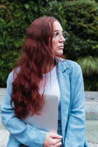 Businesswoman with long red hair holding a laptop