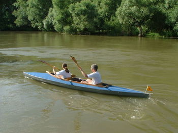 Rear view of man and woman kayaking on river