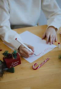A teenage girl writes a letter to santa claus at the table.