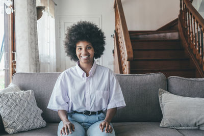 Young woman using digital tablet while sitting on sofa at home