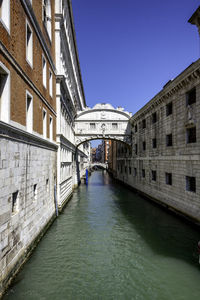 Bridge over canal amidst buildings against sky