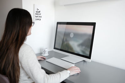 Rear view of woman using mobile phone while sitting on table