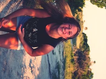 Portrait of smiling young woman against trees