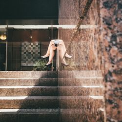 Side view of woman on staircase against wall