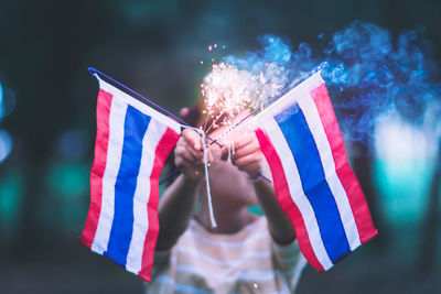 Girl holding sparkler with thai flags during celebration event