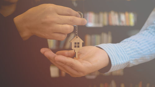 Midsection of real estate agent giving key to man in office