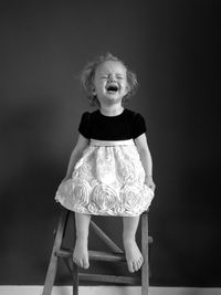 Cute crying girl sitting on stool at home