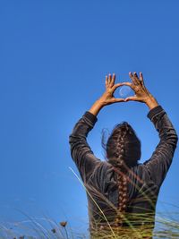 Rear view of woman doing yoga on mountain against clear sky