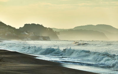 Scenic view of sea against moody sky during sunrise