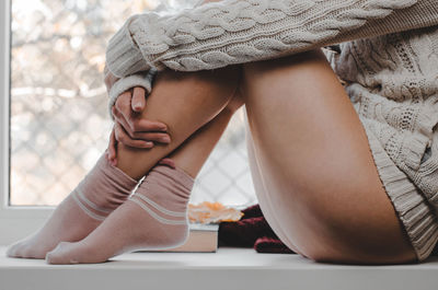 Midsection of young woman sitting at home