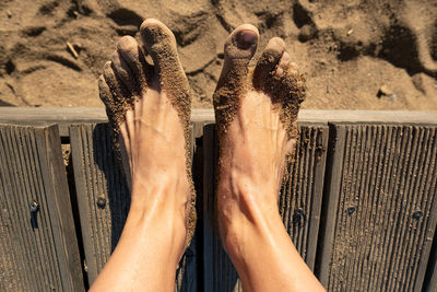 Low section of person standing on sand at beach