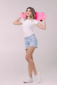 Portrait of young woman standing against wall