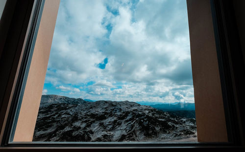 Scenic view of mountains against sky seen through window