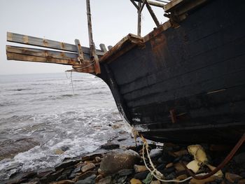 Abandoned boat on beach against sky