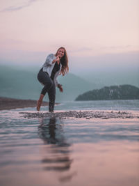 Woman on sea shore against sky during sunset