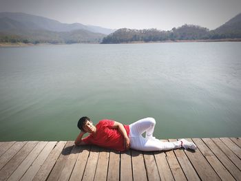 High angle view of man relaxing on pier by lake