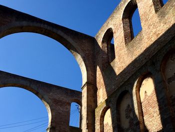 Low angle view of arch bridge against clear blue sky