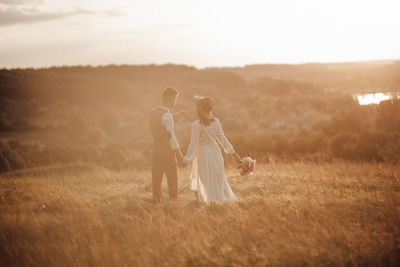 Couple kissing on field against sky